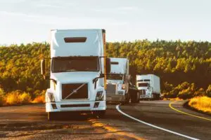 Trois tracteurs à semi-remorque circulent sur la route.