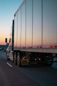 A tractor-trailer driving into the sunset